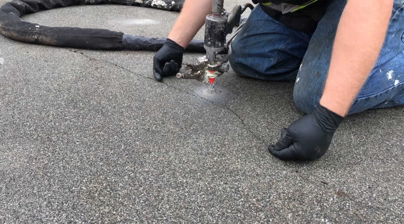 Technician in black gloves using injection equipment to repair cracks in a concrete surface