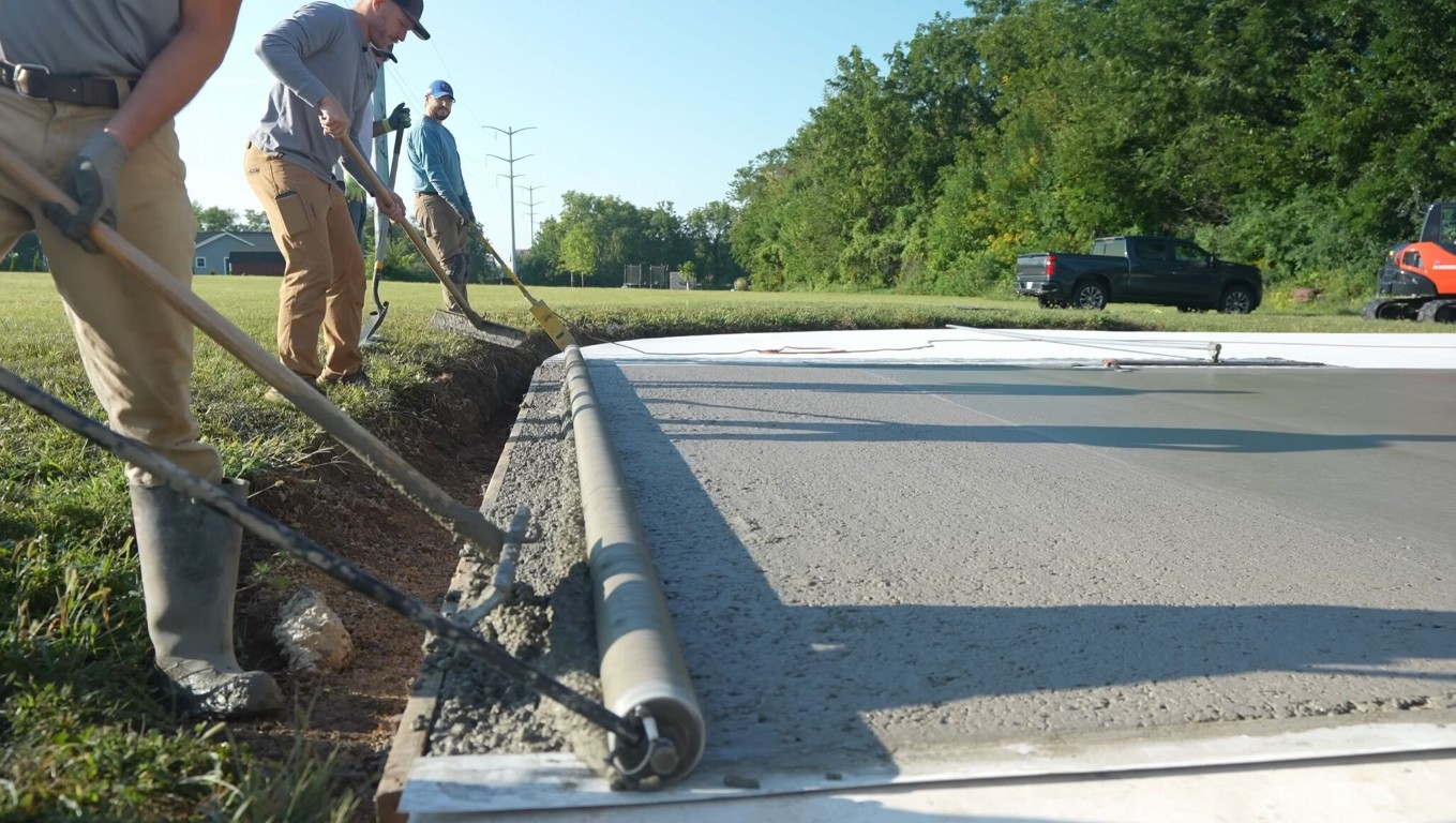 Two workers screeding and finishing a fresh concrete driveway in Sioux Falls, SD