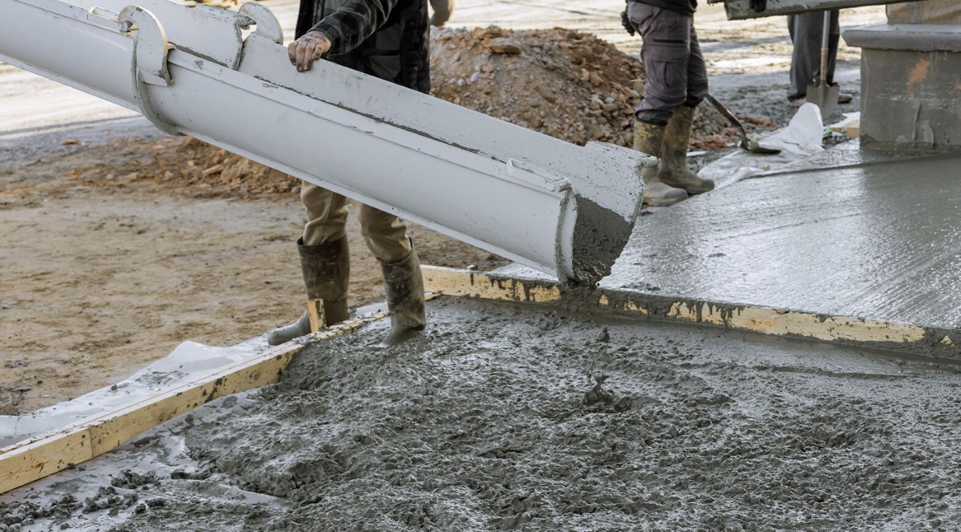 Concrete workers pouring fresh concrete from a truck chute onto a formed slab at a residential job site in Sioux Falls, SD