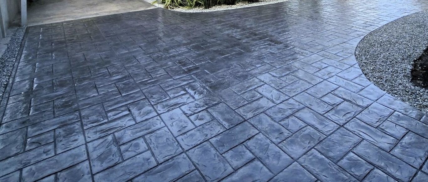 Dark stamped concrete driveway with a herringbone brick pattern and smooth curved border in Sioux Falls, SD